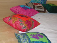 cushions made by Rosie Hobbs using the womens textile work - handmade felt hands and feet embroidered with beads
